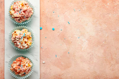 Board with tasty popcorn balls on color background