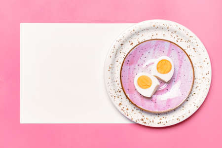 Plate with boiled egg and blank sheet of paper on color backgroundの写真素材