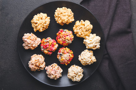 Plate with tasty popcorn balls on dark background