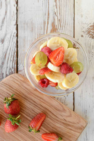 Bowl with fruit salad on wooden backgroundの写真素材