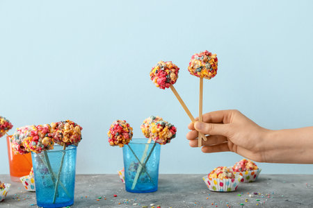 Woman holding tasty popcorn balls on color background