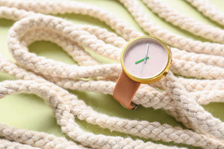 Stylish wrist watch with rope on color background