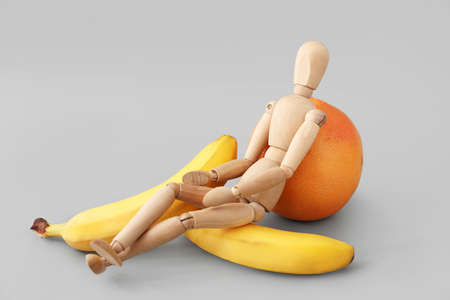 Wooden mannequin and fruits on light background