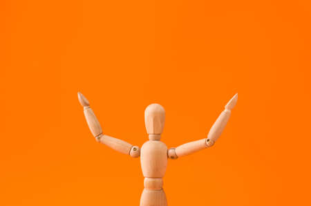 Wooden mannequin raising hands on color backgroundの写真素材