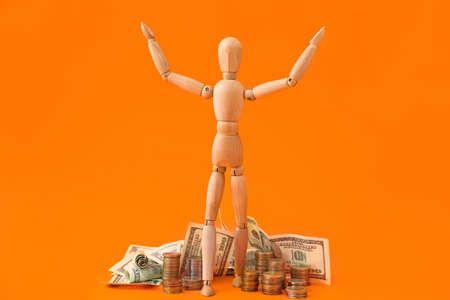 Wooden mannequin with money on color background
