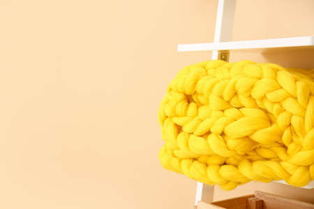 Rack with knitted plaid near color wall in roomの写真素材