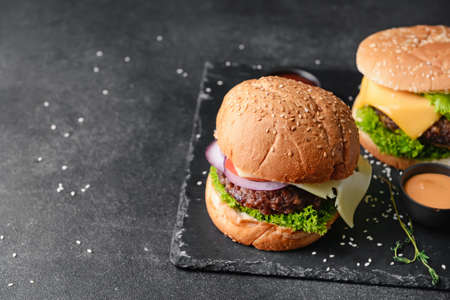 Board with tasty burgers on dark backgroundの写真素材