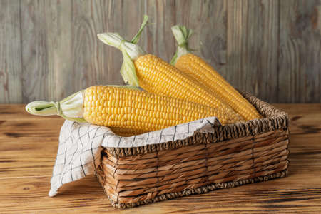Basket with fresh corn cobs on tableの写真素材