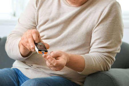 Senior diabetic man checking blood sugar level at homeの写真素材