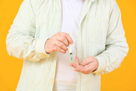 Senior diabetic man taking blood sample with lancet pen on color background