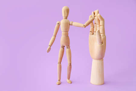 Wooden mannequin and hand on color backgroundの写真素材