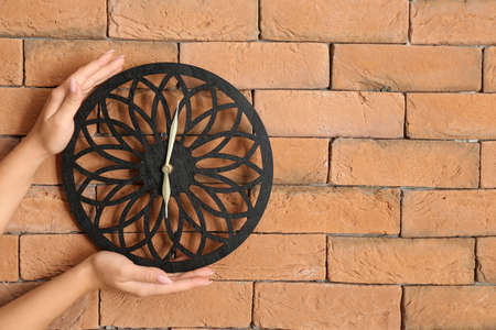 Woman hanging modern clock on wallの写真素材