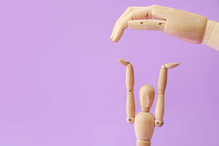 Wooden mannequin and hand on color backgroundの写真素材