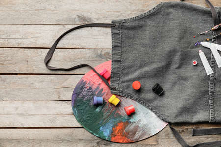 Apron and set of artist's supplies on wooden backgroundの写真素材