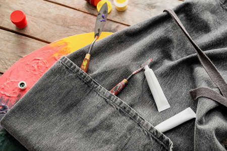 Apron and set of artist's supplies on wooden backgroundの写真素材