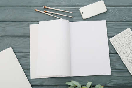 Blank magazine, brushes and mobile phone on dark wooden background