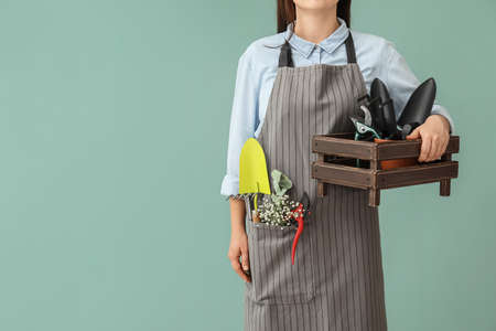 Female gardener with tools on color backgroundの写真素材