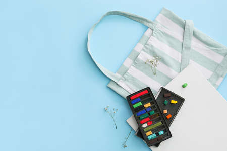 Apron, sheet of paper and chalks on color backgroundの写真素材
