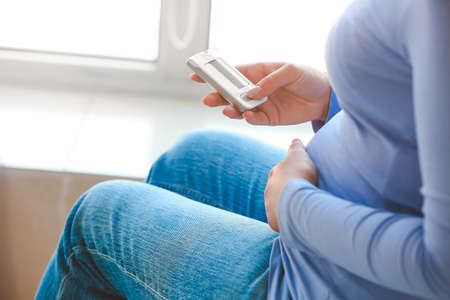 Pregnant diabetic woman measuring blood sugar level at homeの写真素材
