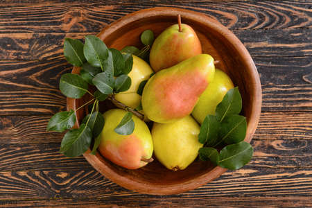 Bowl with fresh pears on wooden background