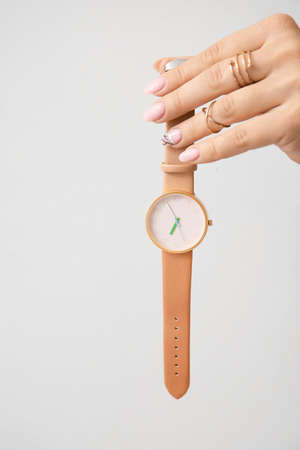 Female hand with stylish wrist watch on light background