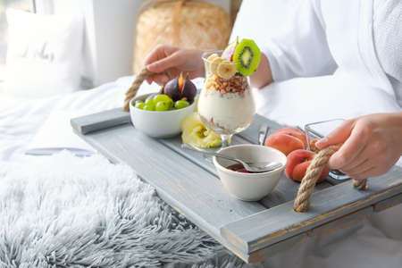 Young woman having tasty breakfast in bed