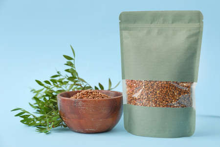 Bag and bowl with buckwheat groat on color background