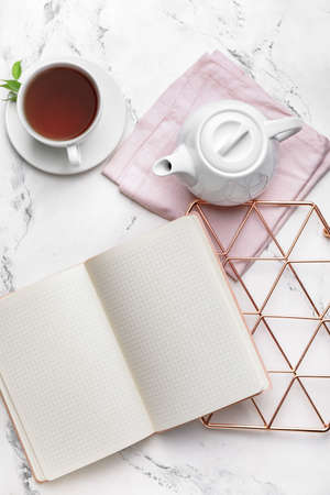 Composition with teapot, blank notebook and cup of tea on light backgroundの写真素材