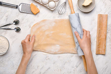 Woman making dough on light background