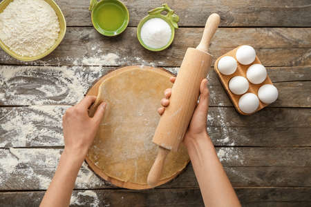 Woman making dough on wooden background
