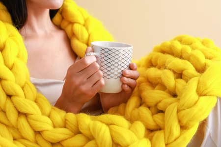 Beautiful young woman with warm plaid drinking tea, closeupの写真素材