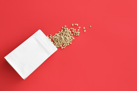 Bag with green coffee beans on color backgroundの写真素材