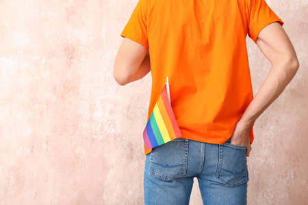 Young man with LGBT flag on color backgroundの写真素材