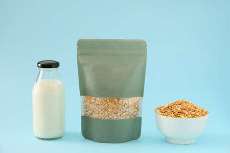 Bag with oat groat and bottle of milk on color background