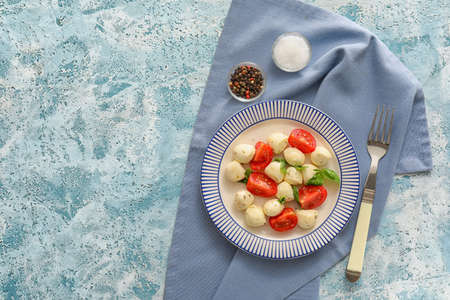 Plate with mozzarella cheese, tomatoes and basil on color backgroundの写真素材