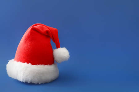 Santa Claus hat on color background