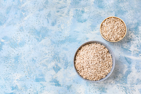 Bowls with sunflower seeds on color backgroundの写真素材