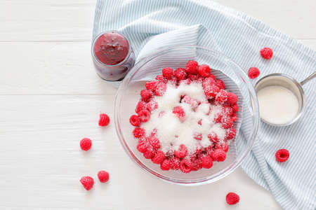 Bowl with ripe raspberry and sugar on wooden background