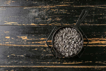 Frying pan with sunflower seeds on dark wooden backgroundの写真素材
