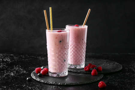 Glasses of delicious smoothie with blueberry and raspberry on dark background