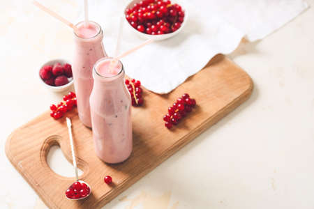 Bottles of tasty smoothie with cranberry and raspberry on light backgroundの写真素材