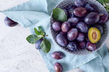 Bowl with tasty plums on light backgroundの写真素材