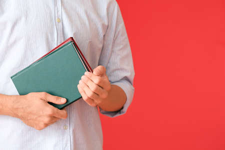 Young man with books on color background, closeupの写真素材