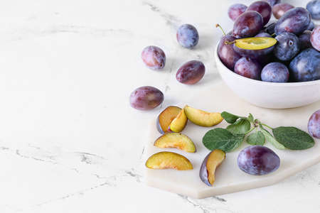 Bowl with tasty plums on light backgroundの写真素材