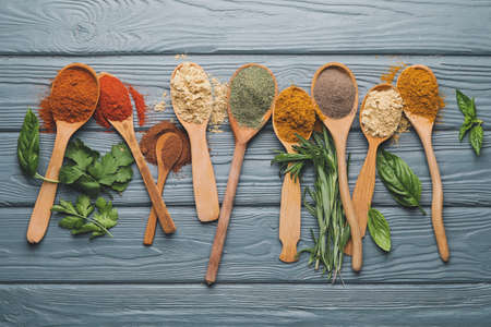 Spoons with different spices and herbs on dark wooden backgroundの写真素材