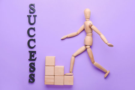 Wooden mannequin with word SUCCESS and cubes on color backgroundの写真素材