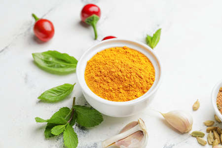 Bowl with turmeric powder on light background