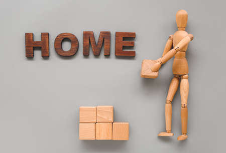 Wooden mannequin with word HOME and cubes on gray backgroundの写真素材