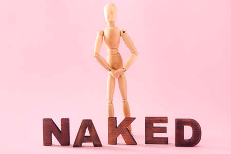Wooden mannequin with word NAKED on color background