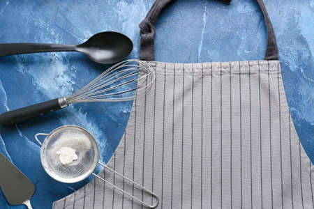 Apron and kitchen utensils on color background, closeupの写真素材